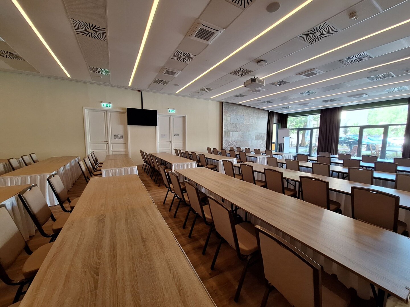 Modern konferenciaterem, tárgyalóasztalokkal és székekkel.